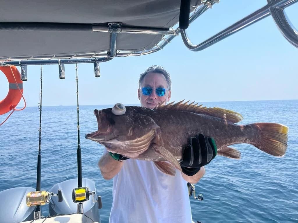 Guest with a large fish caught on a Horizon Blue private fishing charter out of Al Mouj Marina, Muscat